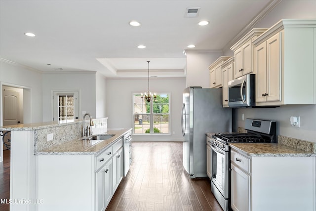 kitchen with sink, an island with sink, stainless steel appliances, pendant lighting, and dark hardwood / wood-style floors