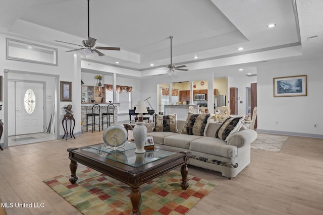 living room with a tray ceiling and light wood-type flooring