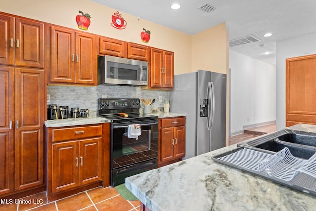 kitchen featuring tasteful backsplash, light stone counters, light tile patterned floors, and stainless steel appliances