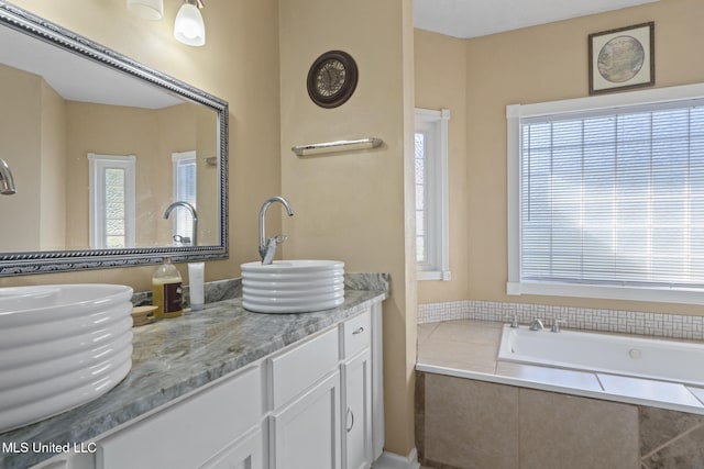 bathroom featuring vanity, tiled bath, and plenty of natural light