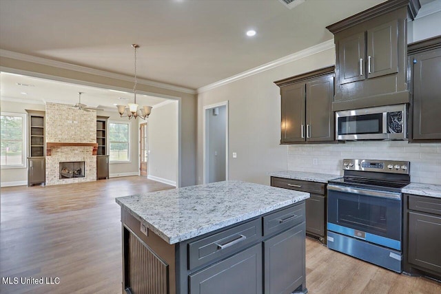 kitchen with a center island, a healthy amount of sunlight, stainless steel appliances, and hanging light fixtures