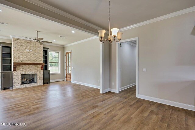 unfurnished living room featuring a stone fireplace, hardwood / wood-style floors, ceiling fan with notable chandelier, and ornamental molding