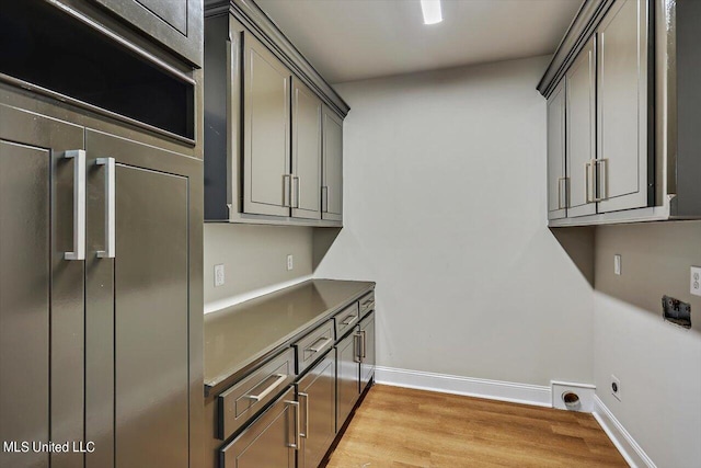 washroom featuring hookup for an electric dryer, light hardwood / wood-style floors, and cabinets