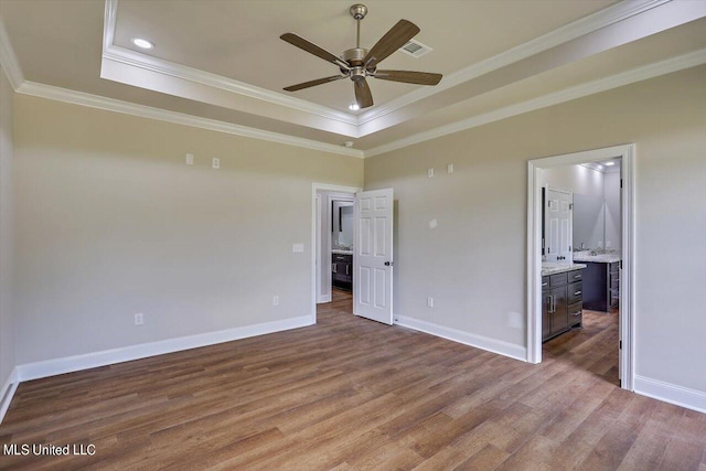 unfurnished bedroom featuring ornamental molding, hardwood / wood-style flooring, connected bathroom, and a tray ceiling