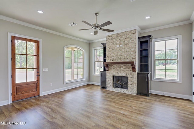 unfurnished living room with ornamental molding, wood-type flooring, a fireplace, and ceiling fan