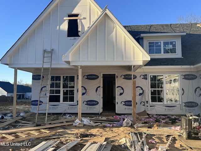 unfinished property with board and batten siding and a shingled roof