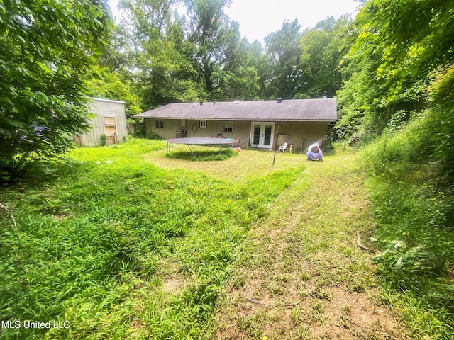 305 Bazinsky Rd, Vicksburg, MS 39180 - back of house featuring french doors, a trampoline, a chimney, and a lawn