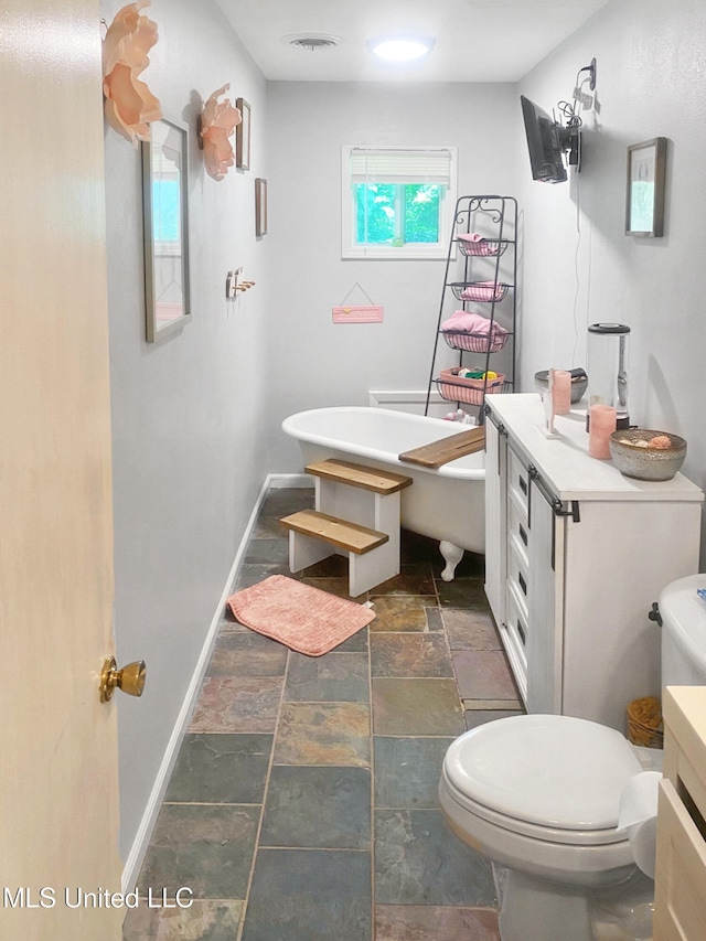 305 Bazinsky Rd, Vicksburg, MS 39180 - bathroom with stone tile flooring, toilet, baseboards, and a soaking tub