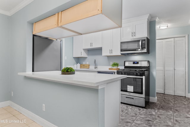 kitchen featuring white cabinets, kitchen peninsula, stainless steel appliances, and ornamental molding