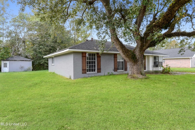 ranch-style home featuring an outbuilding, brick siding, a front lawn, and roof with shingles