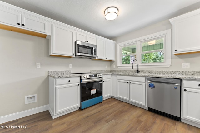 2518 El Viernes St, Gautier, MS 39553 - kitchen featuring appliances with stainless steel finishes, white cabinets, wood finished floors, and light stone countertops