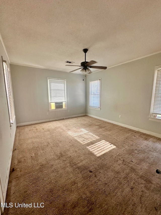 carpeted empty room featuring ceiling fan, a textured ceiling, a wealth of natural light, and ornamental molding