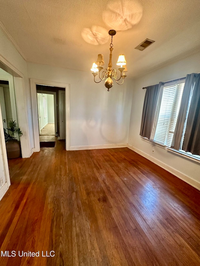 unfurnished dining area featuring an inviting chandelier, a textured ceiling, and dark hardwood / wood-style floors