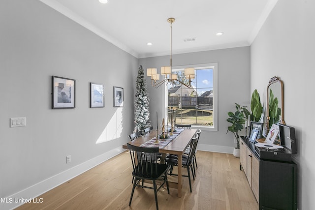 dining space with a notable chandelier, crown molding, and light hardwood / wood-style flooring