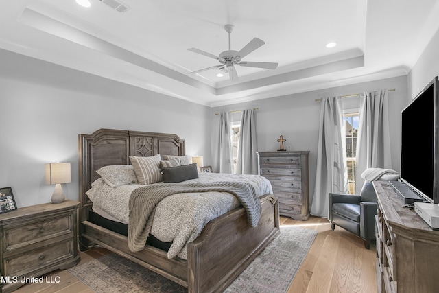 bedroom with access to outside, light hardwood / wood-style floors, a raised ceiling, and ceiling fan