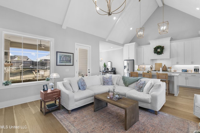 living room with an inviting chandelier, beamed ceiling, and light wood-type flooring