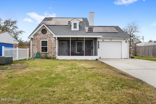 view of front of property with a garage, a front yard, a sunroom, and solar panels