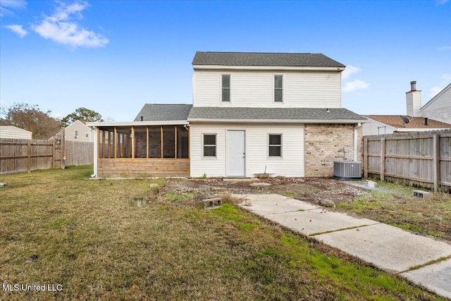 rear view of property with a sunroom, a lawn, and central AC