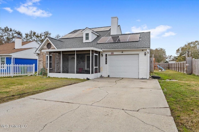 view of front of home with a front yard, solar panels, and a sunroom