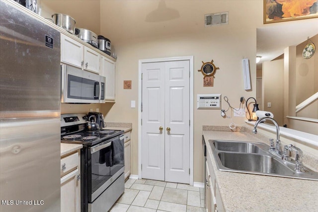 kitchen featuring light tile patterned floors, sink, white cabinets, and appliances with stainless steel finishes