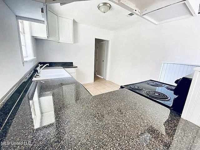 kitchen with sink, electric range oven, dark stone countertops, and white cabinets