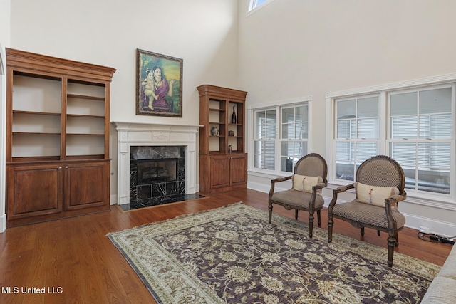 living room featuring dark hardwood / wood-style flooring, a towering ceiling, and a high end fireplace