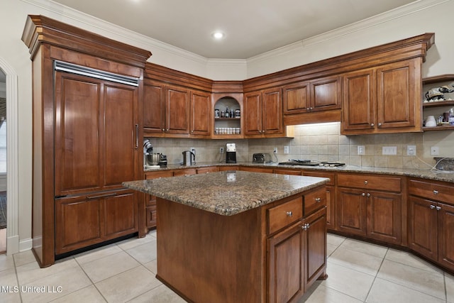 kitchen featuring a center island, dark stone countertops, light tile patterned floors, and decorative backsplash