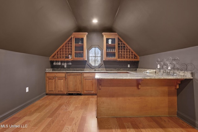 bar with vaulted ceiling and light hardwood / wood-style floors