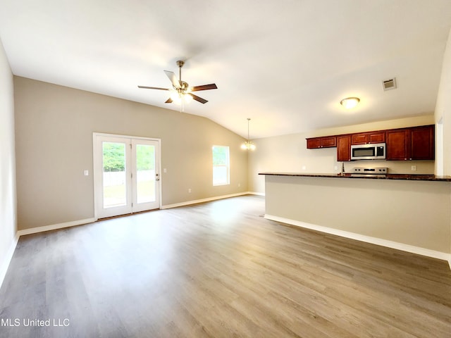 unfurnished living room featuring visible vents, light wood finished floors, ceiling fan with notable chandelier, and lofted ceiling