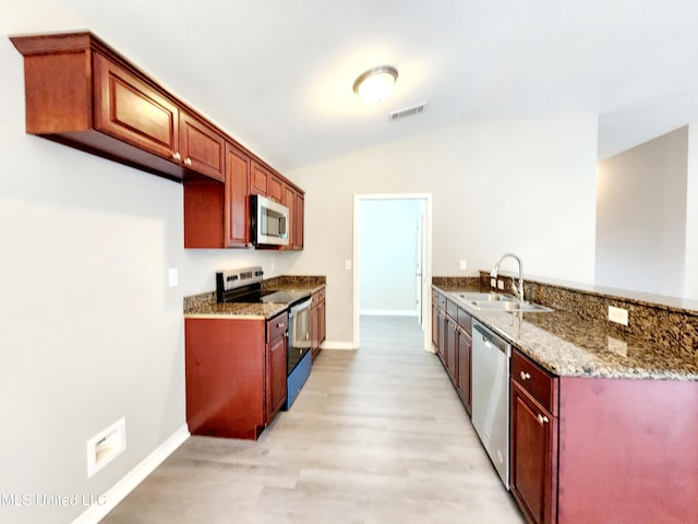 kitchen with appliances with stainless steel finishes, a sink, visible vents, light wood-style flooring, and vaulted ceiling