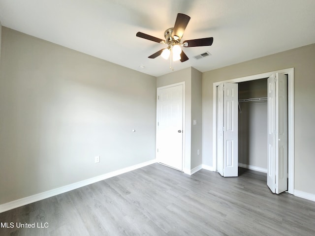 unfurnished bedroom with visible vents, a closet, wood finished floors, baseboards, and a ceiling fan