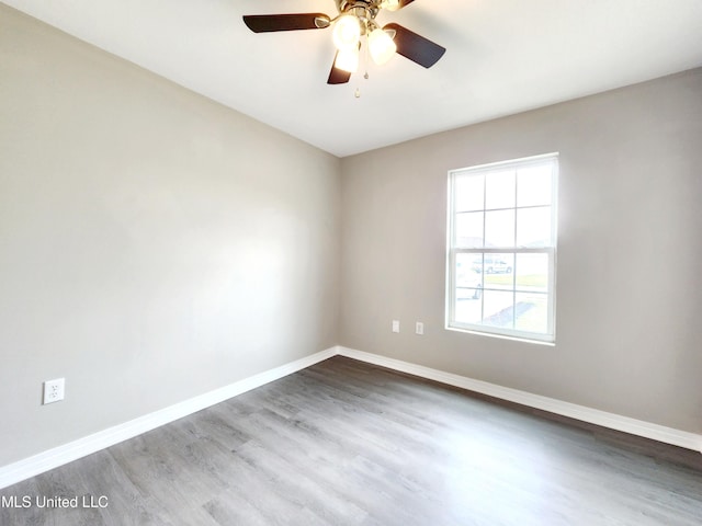 empty room with a ceiling fan, baseboards, and dark wood-type flooring