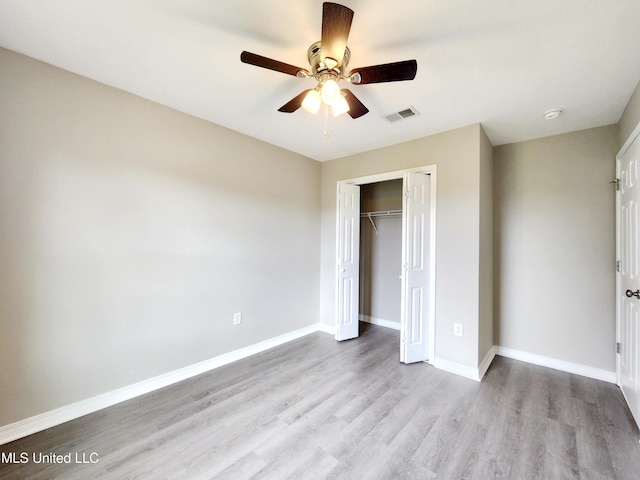 unfurnished bedroom with visible vents, a closet, wood finished floors, baseboards, and a ceiling fan