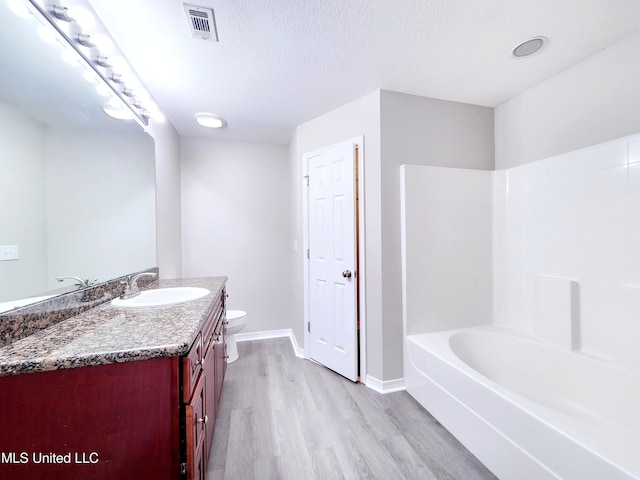 full bath featuring vanity, toilet, baseboards, wood finished floors, and visible vents