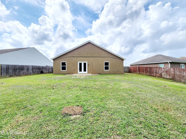 rear view of property featuring french doors, a yard, and a fenced backyard