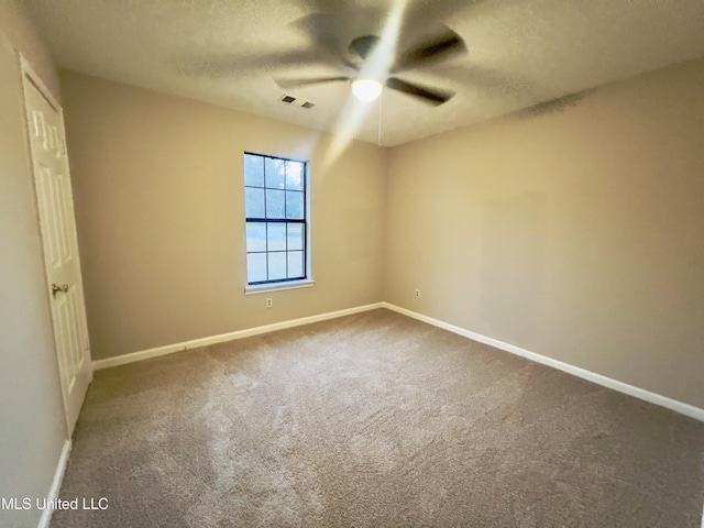 spare room featuring ceiling fan, carpet, and a textured ceiling