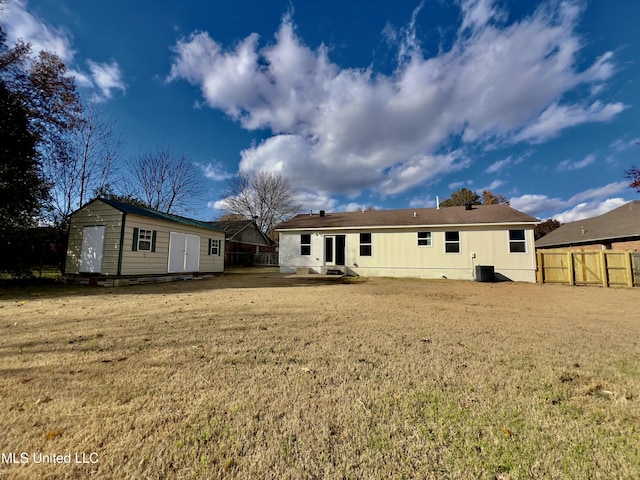 rear view of property featuring a lawn, central AC, and an outbuilding