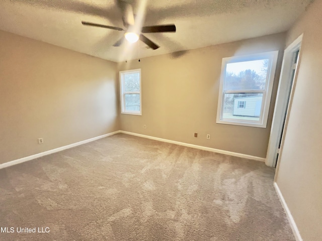 empty room with ceiling fan, carpet floors, and a textured ceiling