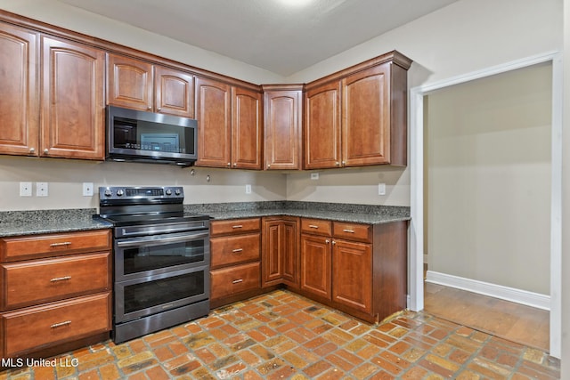 10566 W River Vue, Biloxi, MS 39532 - kitchen with stainless steel appliances, brick floors, and brown cabinetry