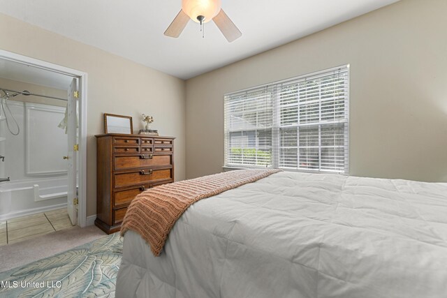 211 Demontluzin Ave, Bay Saint Louis, MS 39520 - bedroom featuring light colored carpet, light tile patterned floors, a ceiling fan, and connected bathroom