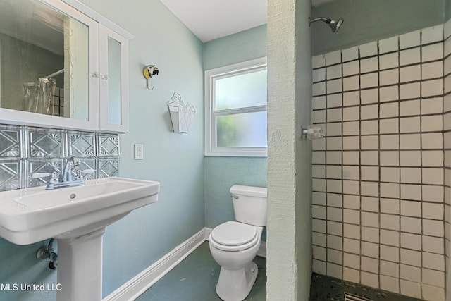 211 Demontluzin Ave, Bay Saint Louis, MS 39520 - full bathroom featuring toilet, tiled shower, baseboards, and a sink
