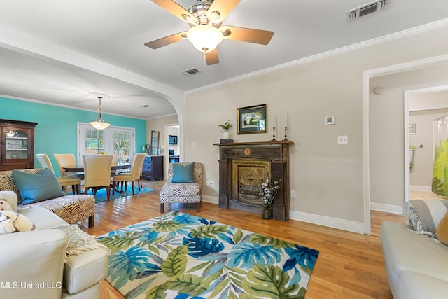 211 Demontluzin Ave, Bay Saint Louis, MS 39520 - living area featuring light wood-style flooring, baseboards, arched walkways, a ceiling fan, and a fireplace