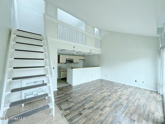 unfurnished living room with a towering ceiling and light hardwood / wood-style flooring