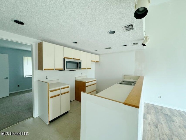 kitchen featuring white cabinetry, sink, and light hardwood / wood-style flooring