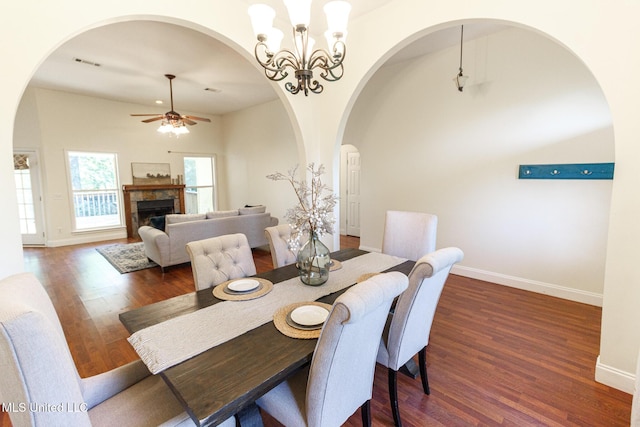 dining area with a fireplace, ceiling fan with notable chandelier, baseboards, wood finished floors, and visible vents