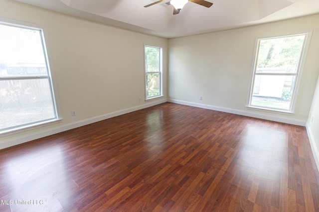unfurnished room featuring baseboards, a ceiling fan, and dark wood-style floors
