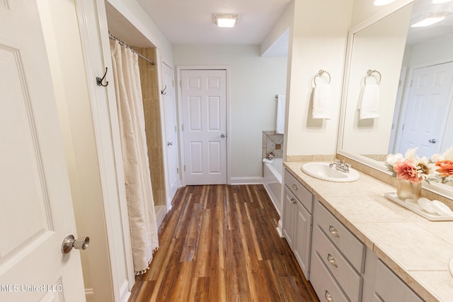 full bathroom with a shower with curtain, a bath, wood finished floors, vanity, and baseboards