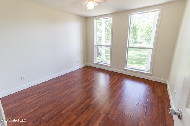 unfurnished room featuring baseboards, a ceiling fan, and dark wood finished floors