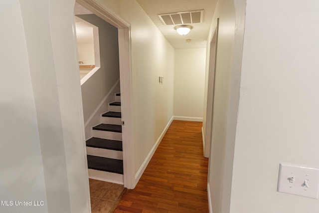 corridor featuring visible vents, baseboards, and wood finished floors