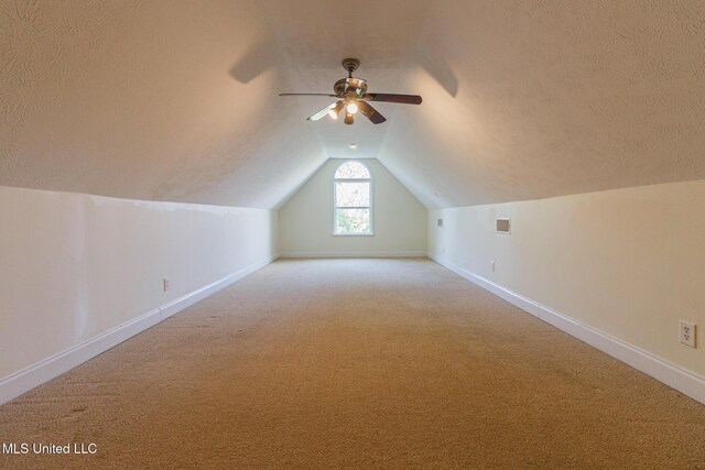 bonus room featuring baseboards, a textured ceiling, lofted ceiling, and light colored carpet